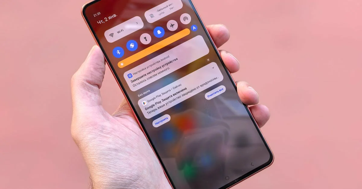 Vue rapprochée d'une personne tenant un smartphone affichant des notifications et des icônes à l'écran.